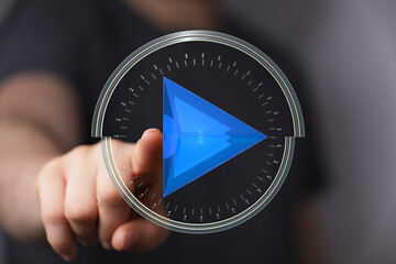 Concept image featuring a person's hand interacting with a glowing play button overlayed on a time clock, symbolizing video, audio, m