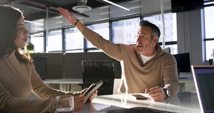 Diverse coworkers discussing project at office table after tablet scrolling and welcoming newcomer