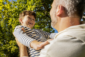 Joyful moments between father and son in a sunny park filled with laughter and love