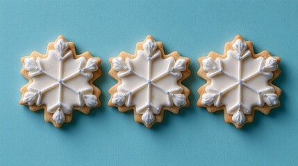 Minimalist setup of three snowflake cookies on pastel blue background, geometric spacing and crisp negative space