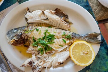 Savor the Mediterranean with this grilled fish dish. Freshly prepared, garnished with parsley and a lemon wedge, it s a healthy and flavorful dining experience.