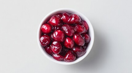 Simple layout of cranberry compote in a small white bowl on pale cream backdrop, soft shadows and generous negative space