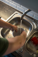 A man washing dishes in the kitchen, home chores, daily routine 