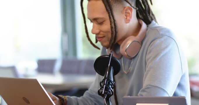 African American man adjusting microphone arm connecting cable and preparing podcast at workspace