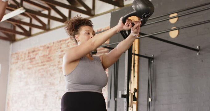 Hip hinge initiating kettlebell swing in gym, woman driving hips forward and building power