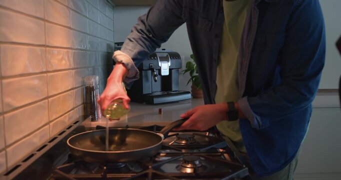 Man is turning on kitchen stove, placing nonstick pan, pouring oil, grabbing meat try to cook