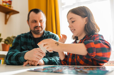 Fototapeta premium Father and daughter doing puzzle at home.