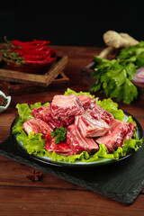 Fresh Raw Beef Ribs with Vegetables on Black Plate