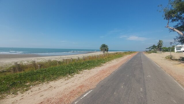 Scenic coastal road beside a tropical beach under a clear blue sky. - Powered by Adobe