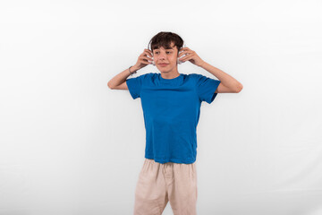 young casual dressed fun happy Gen Z influencer white male model teenage boy with wireless headphones for listening to music podcast or social media from digital device plain background studio setting