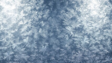 Close up of intricate frost patterns forming on a window pane in winter with a soft light shining through
