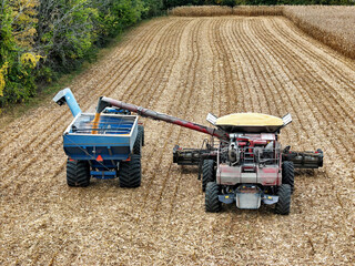 Aerial view of a combine offloading corn into a grain cart being pulled by a tractor