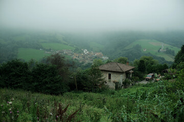 Mountain village on green slopes in light mist. Pedroveya village in Northern Spain