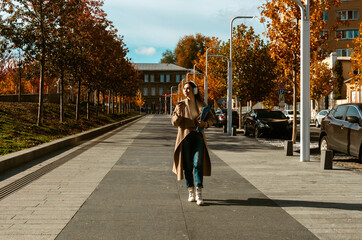 Naklejka premium Woman Walking with Headphones and Coffee in Autumn City