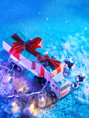 New Year or Christmas card, toy truck transporting gifts, snowy blue background with copy space