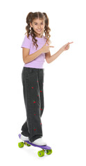 Smiling girl with penny board pointing at something on white background