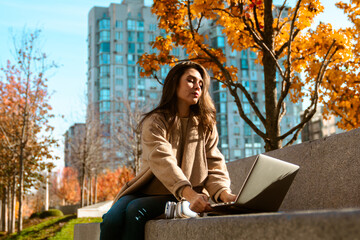 Woman Working on Laptop in Autumn Park
