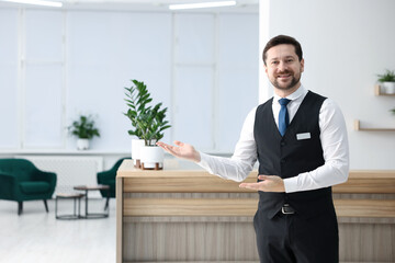 Fototapeta premium Receptionist welcoming near reception desk in hotel, space for text