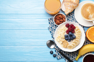 Healthy breakfast. Oatmeal with nuts, banana, berries, jam, coffee and juice served on light blue...