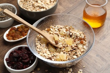 Making granola. Oat flakes with dried fruits in bowl on wooden table, closeup