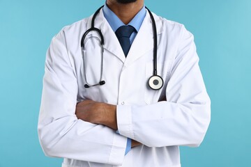 Doctor in medical uniform with stethoscope on light blue background, closeup