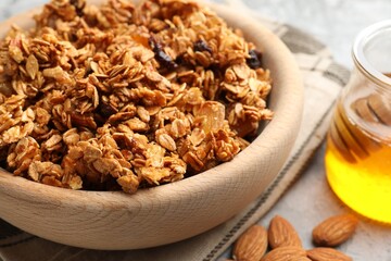 Tasty granola with dried fruits and honey on light grey table, closeup