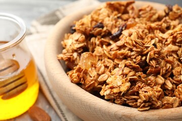 Tasty granola with dried fruits and honey on light grey table, closeup