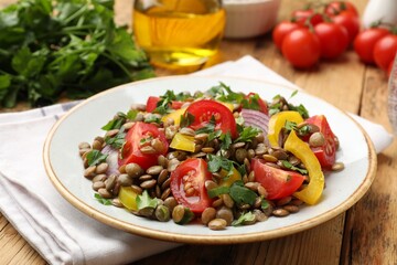 Tasty salad with lentils and vegetables on wooden table, closeup