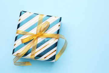 Beautiful wrapped gift on light blue background, top view. Space for text