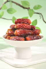 Bowl of fresh dried dates fruit with green leaves natural background healthy organic snack food