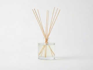 Modern clear glass reed diffuser with pale essential oil and natural rattan sticks isolated on a bright white background