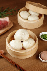 Handmade Chinese Steamed Buns with Meat in Traditional Bamboo Steamers on Wooden Table