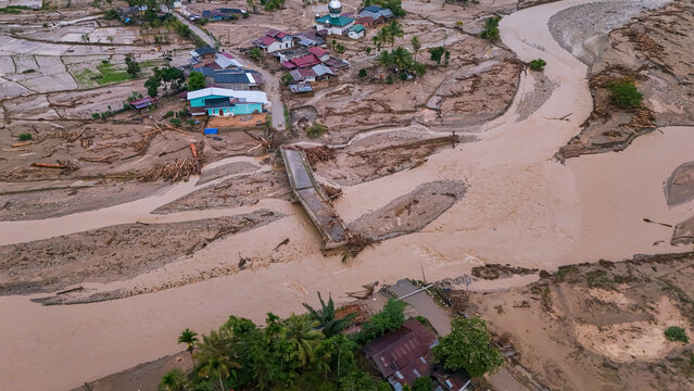 Broken bridge remains amid a devastated village victims of flooding and mudslides seen aerially.