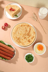 Layered Scallion Pancake with Sausages and Milk on Wooden Table - Traditional Breakfast Meal