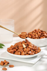 Pine nuts in golden spoon with peeled red seeds on marble table - healthy snack concept