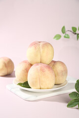 Fresh Yangshan Peaches from Wuxi China Picked Ripe Stone Fruits on White Plate with Green Leaves