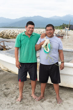 Latin american fishermen friends standing on beach with boat