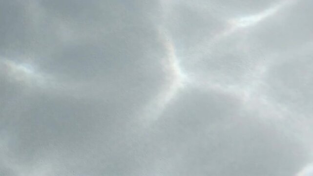 Shimmering caustic light with subtle rainbow prism effects creating a serene pattern on a textured white surface