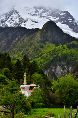Fototapeta premium Buddhist Stupa in Lush Valley Beneath Snow-Capped Himalayan Peaks