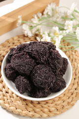 Dried Plum Preserves in Bowl with Flowers - Traditional Asian Fruit Snack on Bamboo Mat
