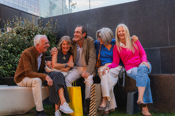 Group of happy senior friends sitting and laughing after shopping during a city outing