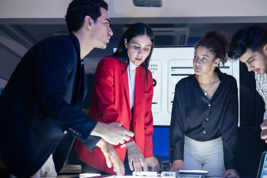 Diverse digital marketing and web development experts intensely discussing UX UI project during a late night brainstorming session. Creative team strategize a new AI application launch at the office