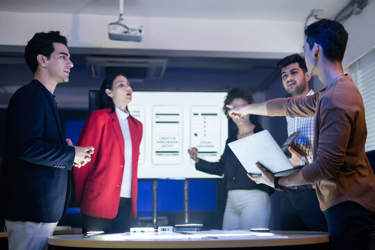 Diverse team of developers and designers having an intense project discussion and strategy meeting. Team reviewing UX, UI and web design on a presentation screen. collaboration, innovative teamwork