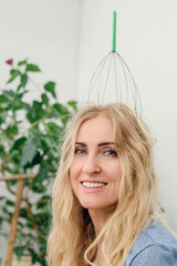 Portrait of beautiful young blonde woman with hair scalp massager. Happy woman with scalp massage tool standing upright on her head