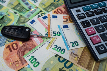 Euro bills with calculator and car key representing vehicle financing, investment and budgeting concept