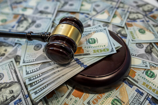 Judge gavel on dollar bills representing justice and financial decision