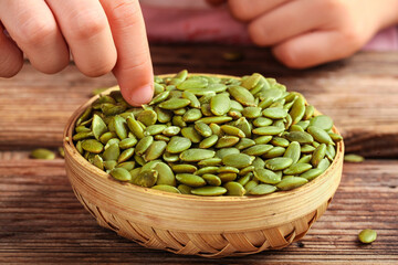 Shelled Pumpkin Seeds in Woven Basket with Hand, Studio Food Shot