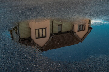 House reflected on the surface of the water on the street