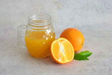 Fresh Orange Juice in a Glass Jar with Whole and Sliced Oranges cut out