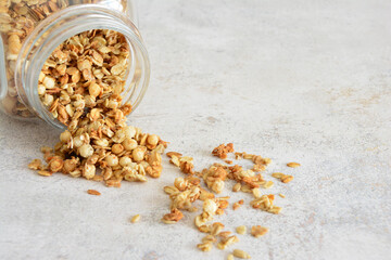 Granola spilling from a glass jar on a rustic surface blank space